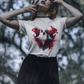 A woman wears a white t-shirt with a bloody ghost design and a black skirt.
