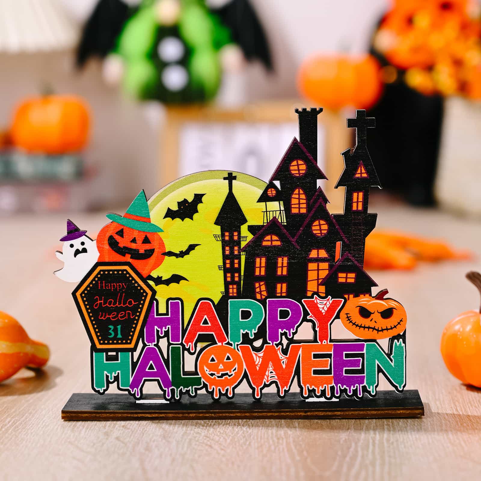 A wooden Halloween ornament with a haunted house, pumpkins, and "Happy Halloween" text.