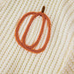 Close-up of a cream knit sweater with an orange pumpkin outline.