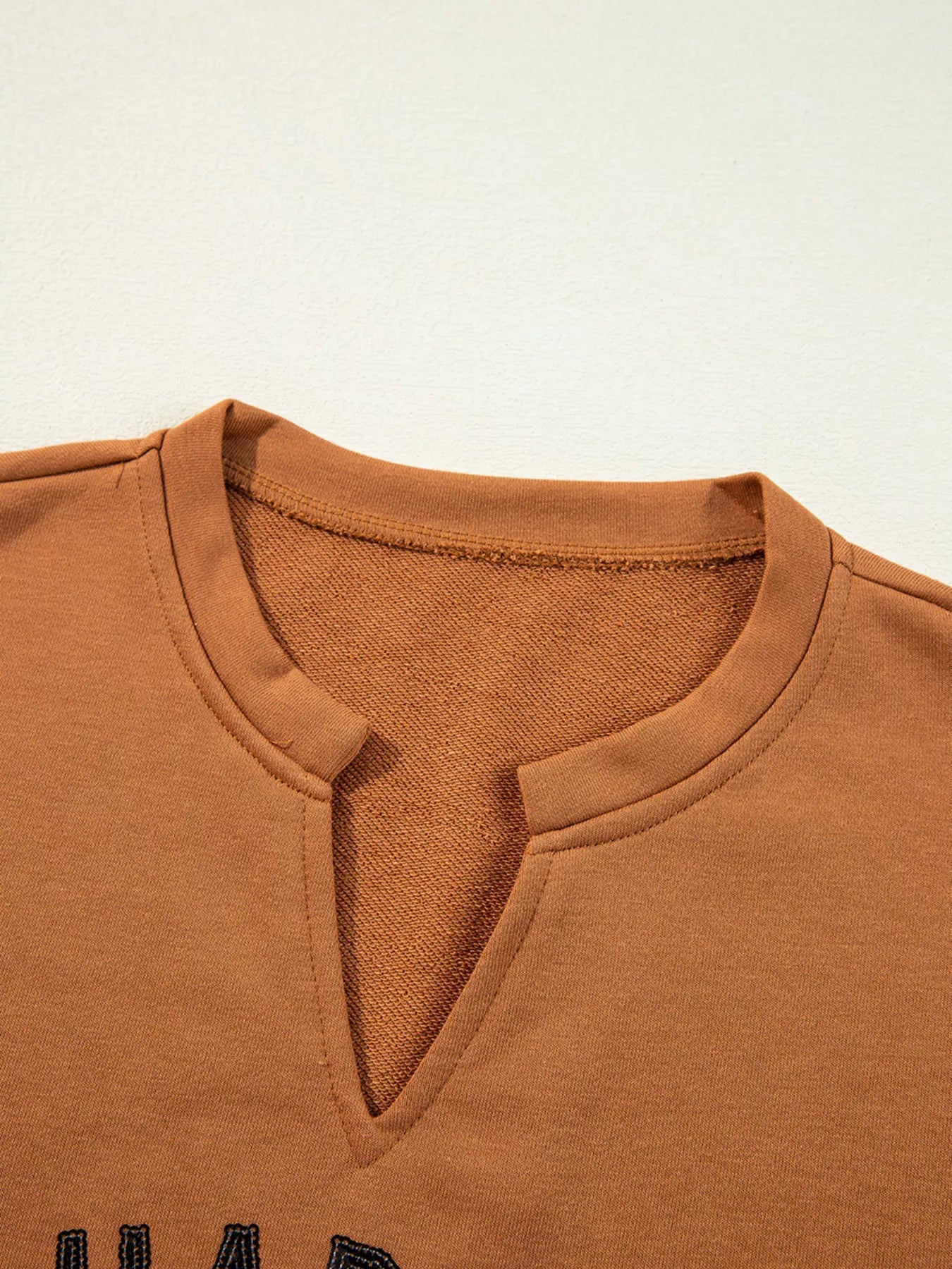 Happy Halloween graphic notched long sleeve loose top in a warm brown color.