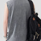 Back view of a man wearing a gray, acid-washed tank top and a black backpack.