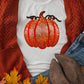 White short sleeve t-shirt with a sequin pumpkin design, paired with a rust cardigan.