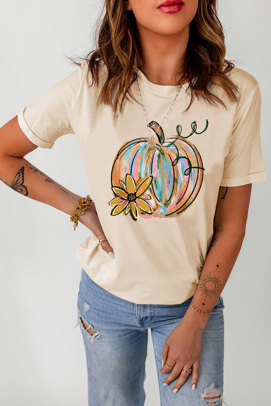 A woman wears a cream short-sleeve t-shirt with a colorful pumpkin graphic.