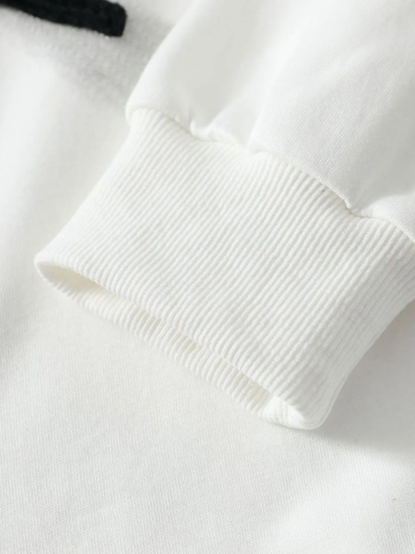 Close-up of a white hoodie sleeve with a ribbed cuff.