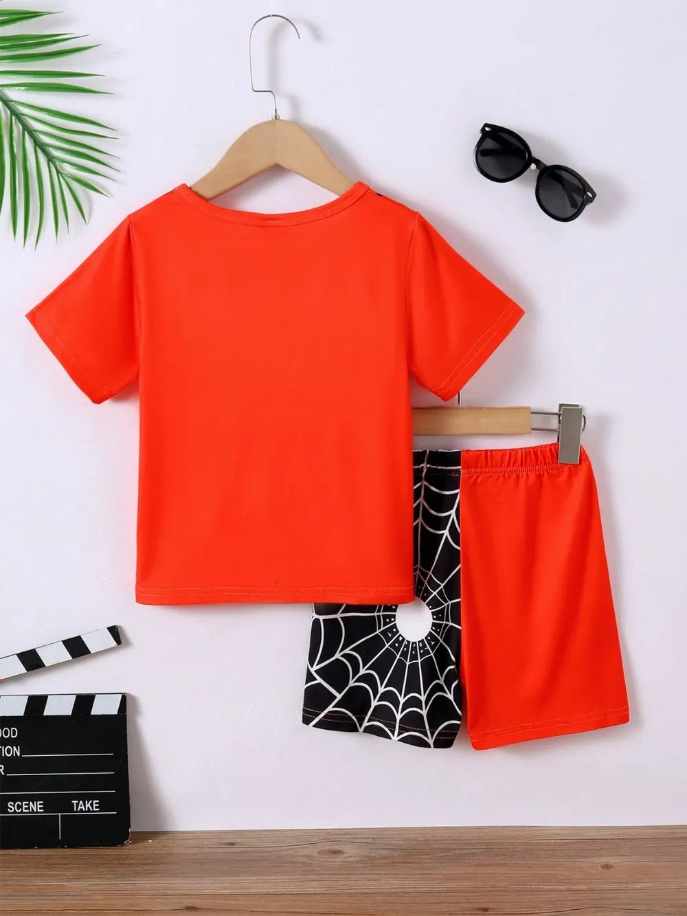 Children's orange short-sleeve t-shirt and black spiderweb shorts set.