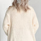 Back view of a woman wearing a cream knit cardigan with a sheer white hair bow.