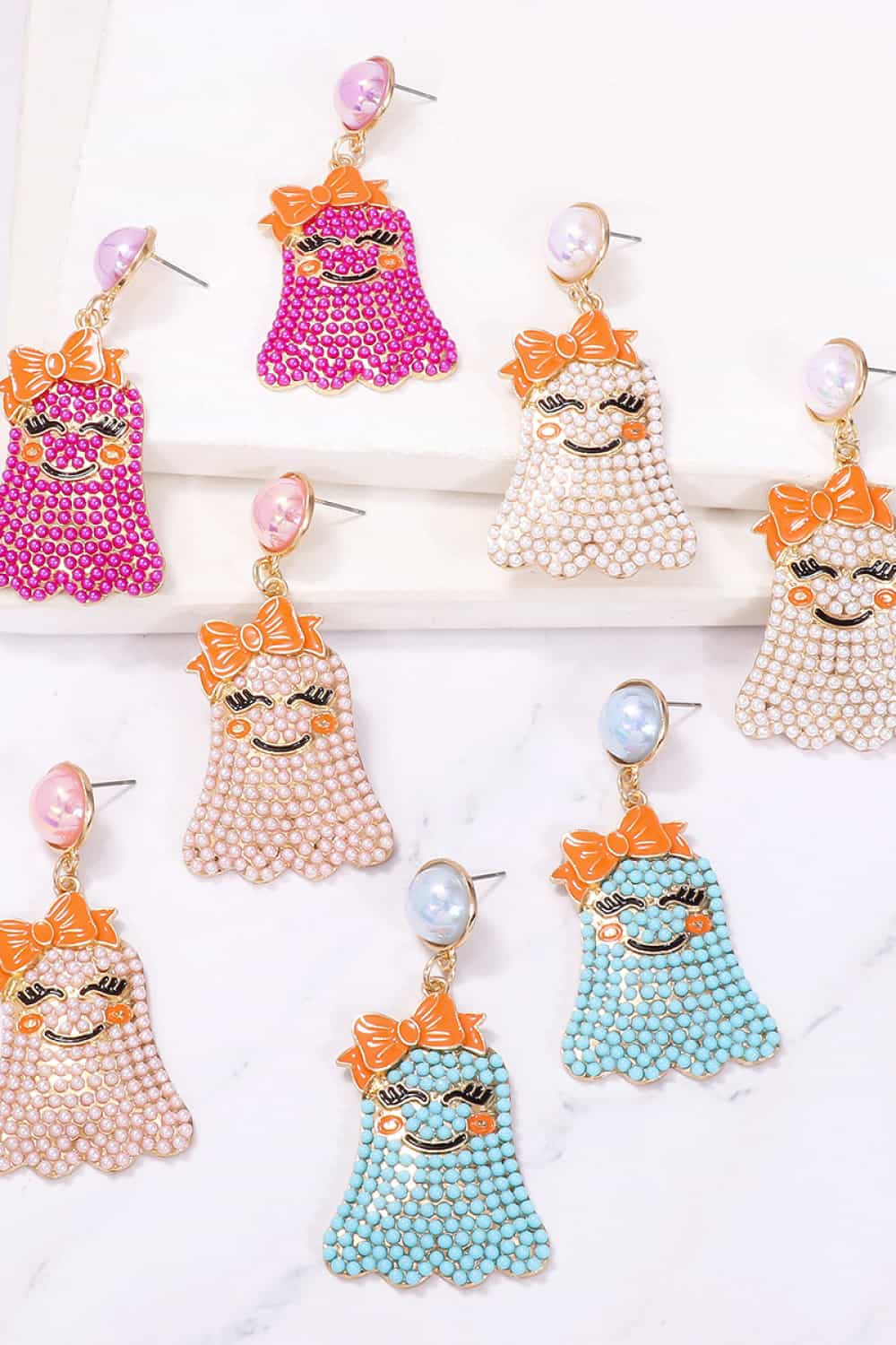 Smiling ghost shape synthetic pearl earrings in various colors.