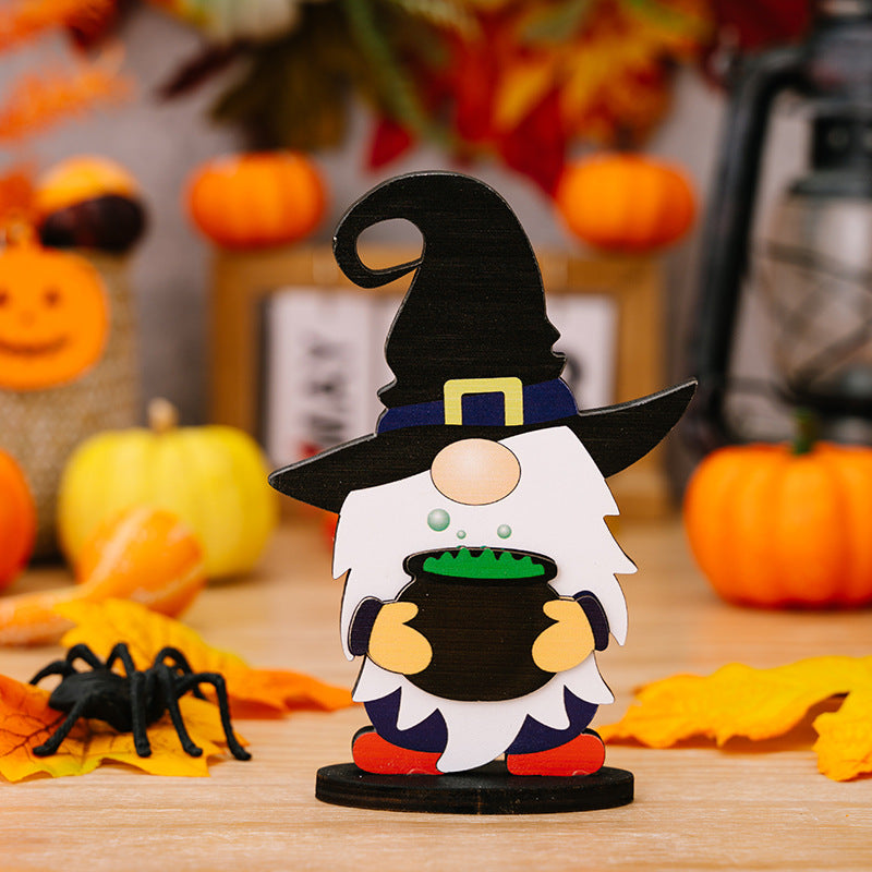 A wooden Halloween gnome ornament wearing a witch hat and holding a cauldron.