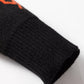 Close-up of a black cardigan sleeve with an orange pumpkin pattern and ribbed cuff.