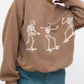 Oversized brown sweatshirt with three white skeleton graphics skateboarding.