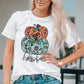 A woman wears a white short-sleeve t-shirt with a pumpkin graphic.