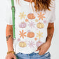 A woman wears a white short-sleeve t-shirt with a pumpkin and flower print.