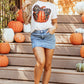 A woman wears a white short-sleeve t-shirt with a pumpkin and leopard print bow.