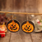 A pair of orange glitter pumpkin earrings with black circular backings hangs from a branch.