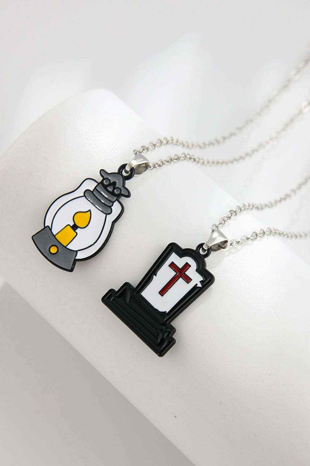 Two necklaces, one with a lantern pendant and the other with a tombstone pendant.
