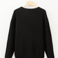 Black round neck long sleeve sweater on a hanger.