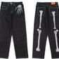 Men's black straight-leg jeans with skeleton hand embroidery on the front and leg bones on the back.
