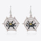 A pair of beaded Halloween-themed spiderweb earrings with a black and yellow spider.