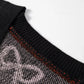 Close-up of a black cardigan with a white and orange pattern.