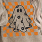 A person wears a beige corduroy long-sleeve sweatshirt with an orange checkered ghost design.