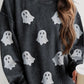 A woman wears a dark gray long-sleeve sweatshirt with glitter ghost graphics.