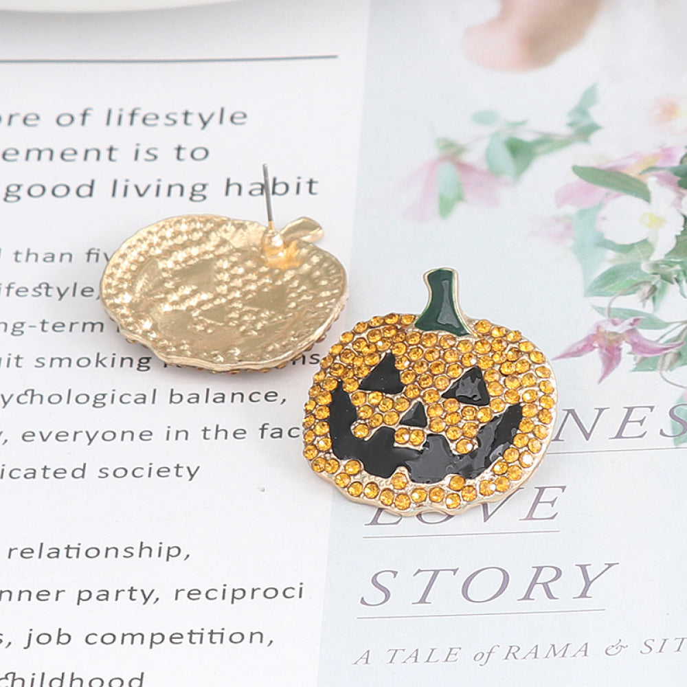 A pair of gold-backed pumpkin earrings with orange rhinestones and black jack-o'-lantern faces.