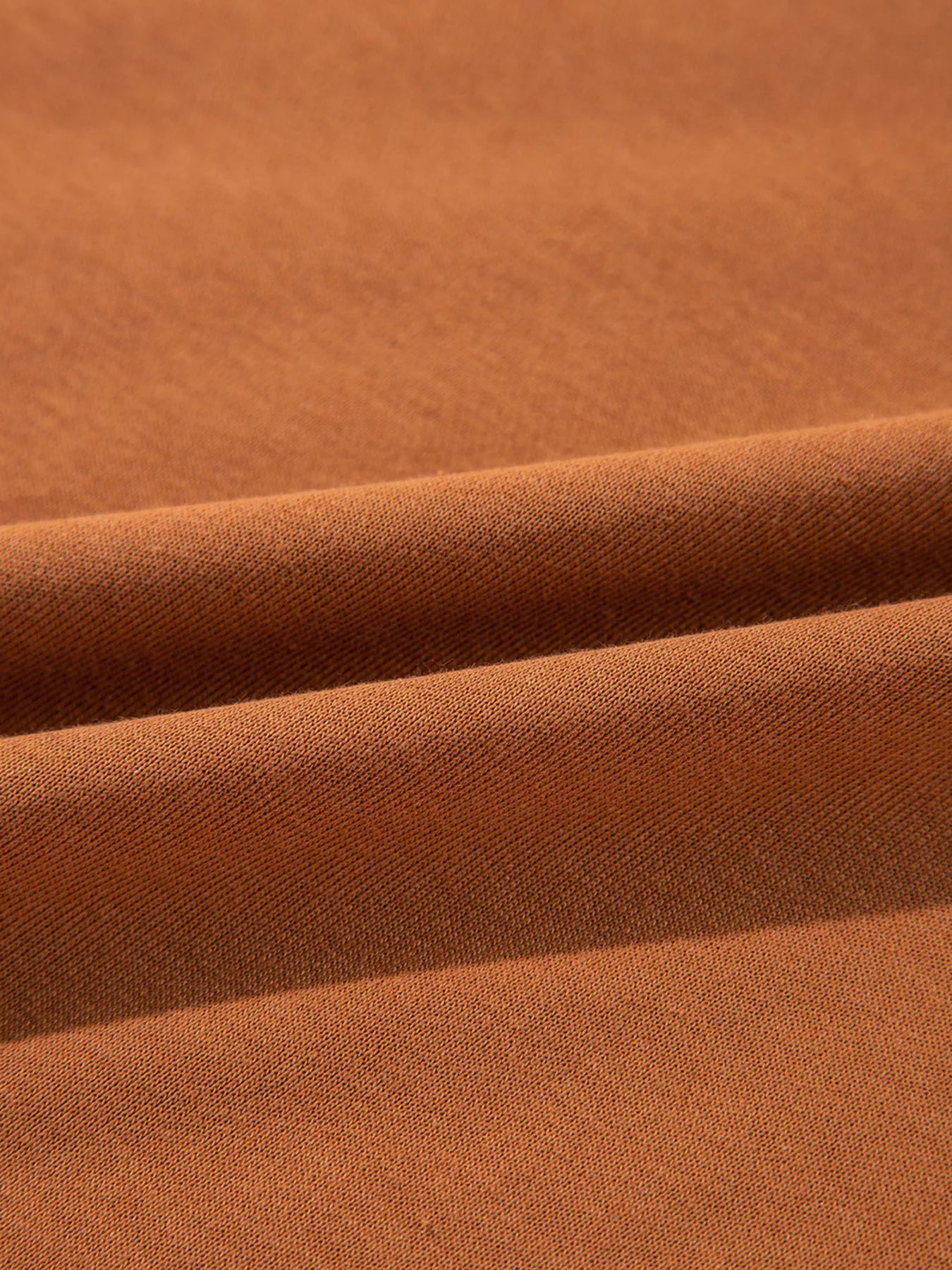 Close-up of a folded, solid brown, slightly stretchy fabric.