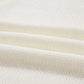 Close-up of a cream-colored knit fabric with three horizontal folds.
