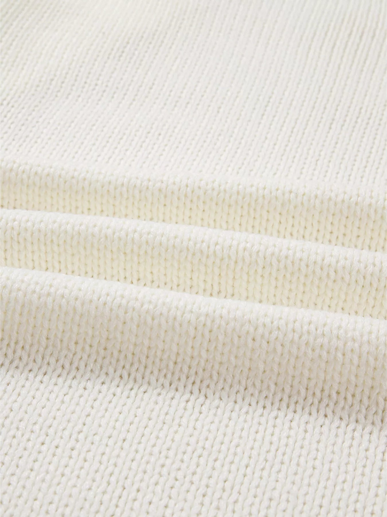 Close-up of a cream-colored knit fabric with three horizontal folds.