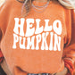 A woman wears an orange "HELLO PUMPKIN" graphic sweatshirt with blue jeans.