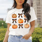 A woman wears a white short-sleeve t-shirt with pumpkin and bow graphics.