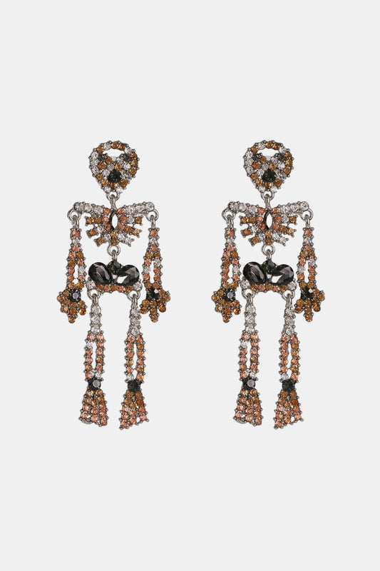 Skeleton-shaped dangle earrings adorned with clear, brown, and black glass stones.