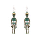 Two antique bronze skeleton earrings with teal accents hang against a white background.