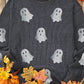 A dark gray long-sleeve sweatshirt with glitter ghost graphics is styled with autumn decor.