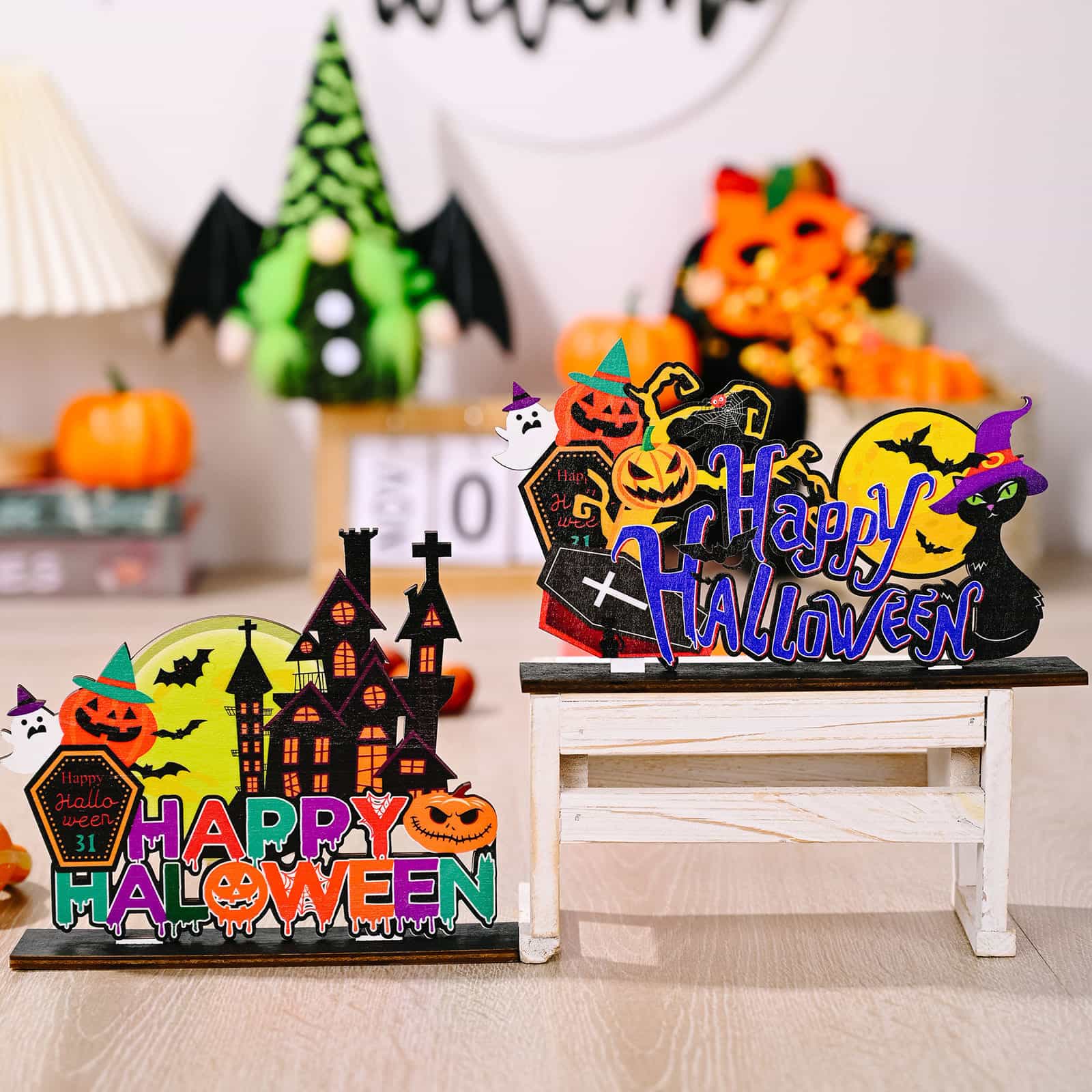 Two wooden Halloween ornaments, one with a haunted house and the other with a black cat.