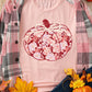 Pink long-sleeve t-shirt with a floral pumpkin graphic, paired with a plaid shirt.
