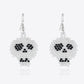 A pair of white beaded skull earrings with black eyes and nose.
