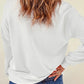 A woman from behind wears a white long-sleeve sweatshirt and blue jeans.