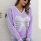 A woman wears a purple skeleton pattern v-neck long sleeve pullover sweater.