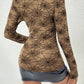 Spider web print long sleeve blouse worn with a black mini skirt and boots.