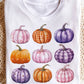 White long-sleeve sweatshirt with nine colorful pumpkin graphics.