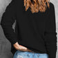 A woman from behind wears a black dropped shoulder sweatshirt and distressed jeans.