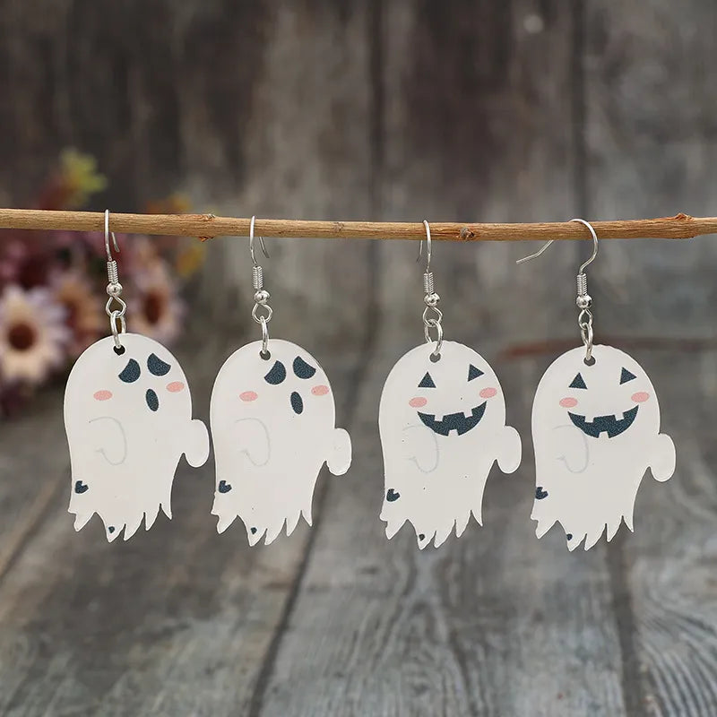 Four ghost-shaped dangle earrings hang from a wooden branch.