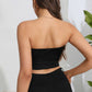 A woman from behind wears a black tube top and black pants.