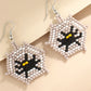Beaded Halloween theme earrings featuring a black spider with yellow eyes on a web.