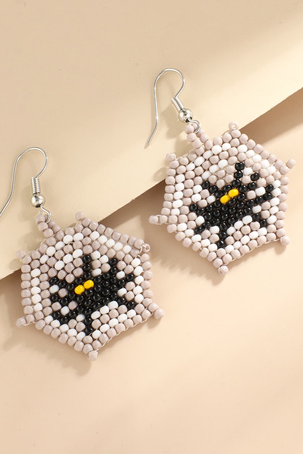 Beaded Halloween theme earrings featuring a black spider with yellow eyes on a web.