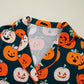 A dark green short sleeve top with an orange and white pumpkin print.