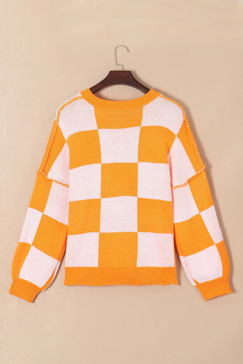 Pumpkin checkered round neck long sleeve sweater on a hanger.