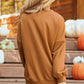 Blonde woman from behind wearing a loose, long-sleeve, brown top.