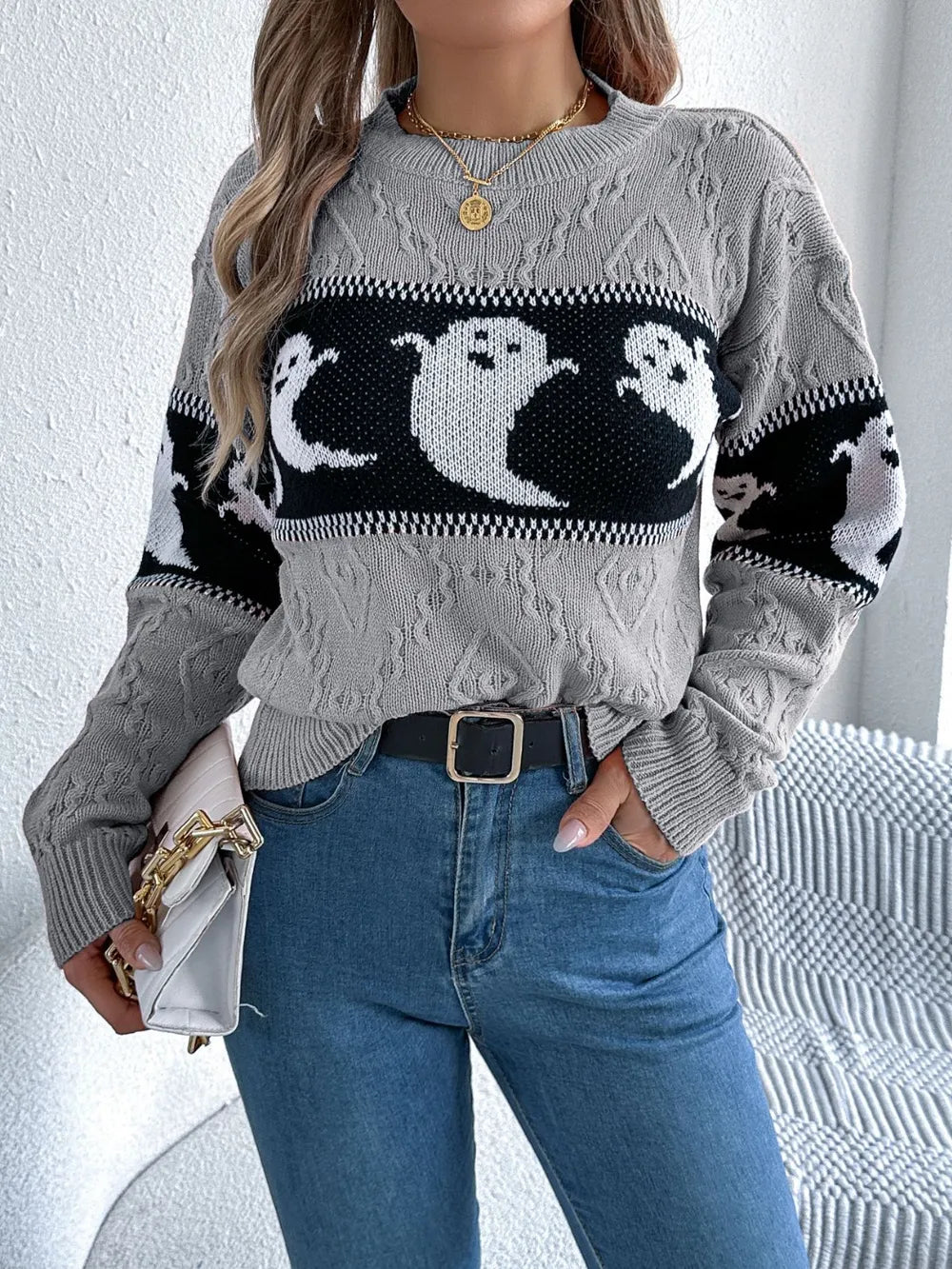 A woman wears a gray long-sleeve sweater with a black and white ghost pattern.